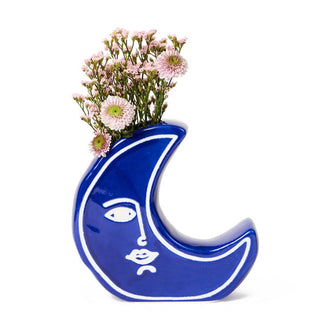 Blue crescent moon vase holds a small arrangement of pink flowers