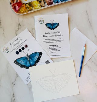 Components of a Blue Morpho butterfly Watercolor Painting Kit on a marble tabletop with paint palette