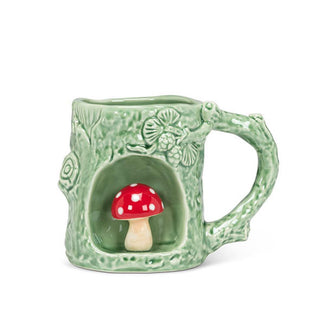 Green mug with rustic texture and tree branch designs features a circular alcove with a red and white amanita mushroom figurine inside