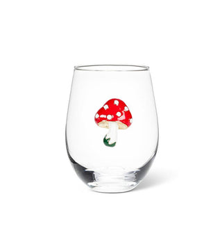 Clear glass stemless wine glass features an enamel red-capped mushroom decal with white spots and a green-accented stem