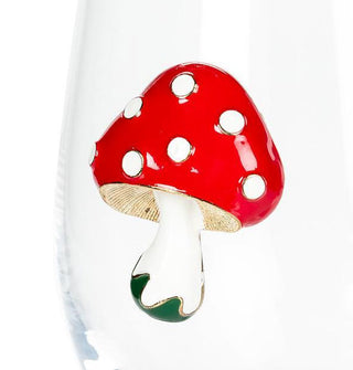 Closeup of the enameled mushroom decal on a clear stemless wine glass shows a red cap with white spots, a gold underside, and a white stem with gold-edged green base