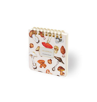 Small white square notepad with gold spiral binding features colorful mushroom illustrations and a central "Journal" title block accented in gold foil