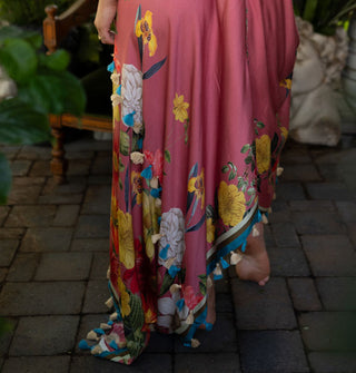 Pink dress skirt with colorful floral designs is finished in contrast stripes and tassels along the bottom hem