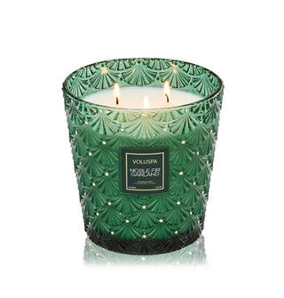Noble Fir Garland Voluspa with three lit wicks in an embossed green glass vessel