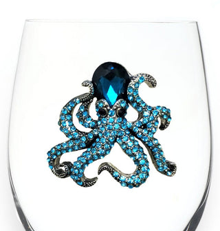 Closeup of a blue bejeweled octopus on the bowl of a clear wine glass