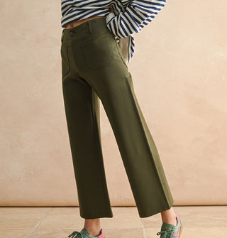 Model wears a pair of cropped flared olive green pants with pockets, belt loops, and button closure