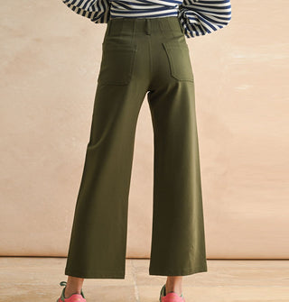 Model wears a pair of cropped flared olive green pants with pockets and belt loops