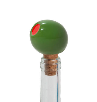 A ceramic green pimento olive and cork stopper is placed in the opening of a clear glass bottle