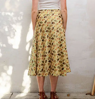 Model facing away from the camera wears a calf-length skirt with print of olives and a flared silhouette