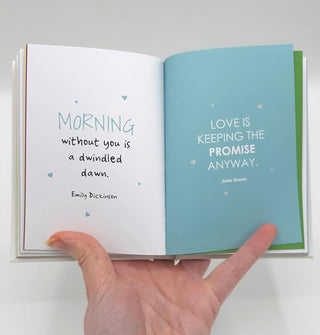 Model's hand holds Olive You open to a page spread featuring quotes by Emily Dickinson and John Green