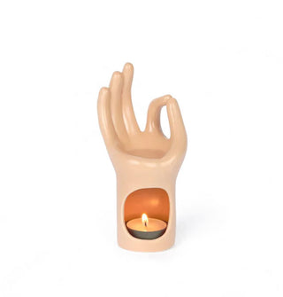 Ceramic essential oil burner in the shape of a hand making a mudra gesture with a tea light inside the wrist base and oil pooled in the palm