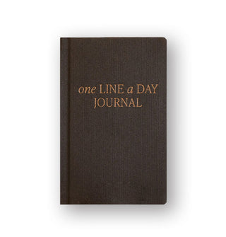 Charcoal fabric-covered journal says, "One line a  day journal" in alternating uppercase and lowercase italic gold foil lettering