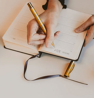 Model writes in a five-year lined journal with attached ribbon bookmark