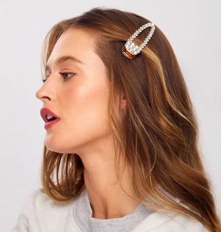 Model wears a rhinestone-encrusted gold hair clip with open shape to the side, holding back shorter front hair pieces
