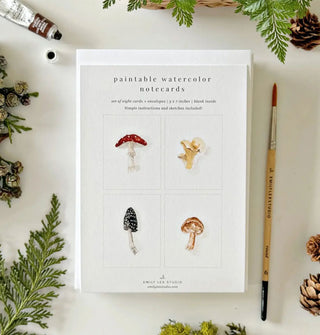 Paintable Watercolor Notecards staged with paintbrush, paint tube, greenery, and pine cones