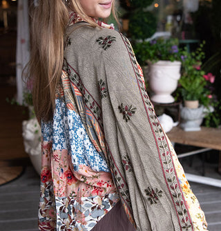 Model wears a patchworked floral print shirt with floral embroidery down the sleeves