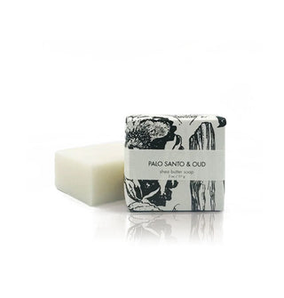 Bar of white soap alongside its "Palo Santo & Oud" packaging which features black and white floral illustrations