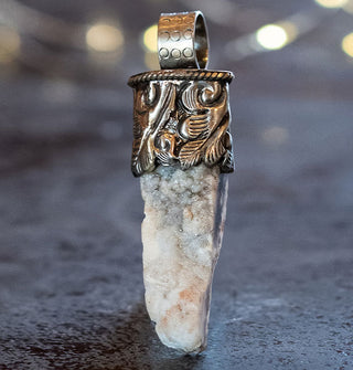 Light-colored orca agate in engraved silver pendant setting with round top bail