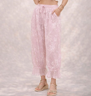 Model wears light pink pantaloons with flocked velvet floral pattern, elasticated tie waist, and lace trim