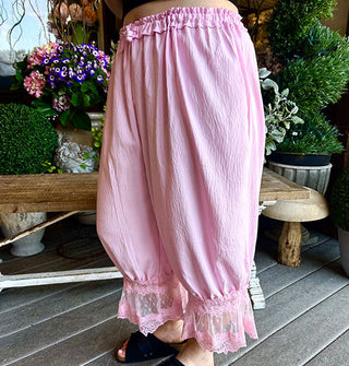 Model wears bubblegum pink lace-trimmed bloomers with a ruched waistband