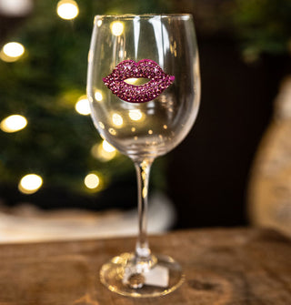 Clear wine glass is embellished with a jewel-encrusted pink lips decal on its bowl