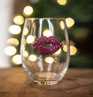 A clear stemless wine glass features a pink lips decal fully bejeweled in pink rhinestones