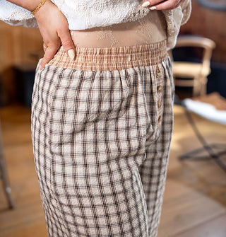 Closeup of the elastic waist on a pair of two-tone plaid pants with button placket