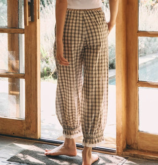 Model standing in a doorway wears plaid bloomer-style pants with elasticated, lace-trimmed ankle cuffs