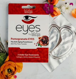 Foil pack and outer sleeve of ToGoSpa Pomegranate Eyes masks staged with fresh flowers