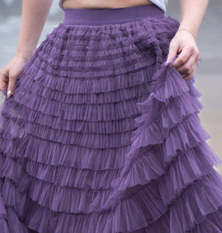 Model wears a multi-tiered ruffled purple tulle skirt with an elastic waistband