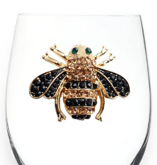 Closeup of a jewel-encrusted black and gold bee decal on the side of a clear wine glass