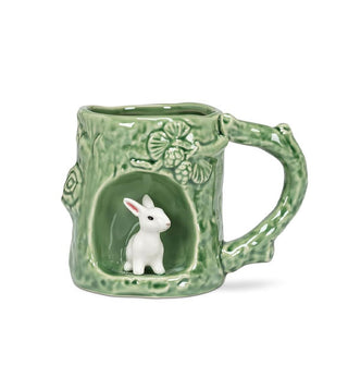 Green mug with rustic texture and tree branch designs features a circular alcove with a white rabbit figurine inside