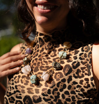 Smiling model in a leopard print tank top wears a necklace composed of colorful crystals wrapped in gold wire