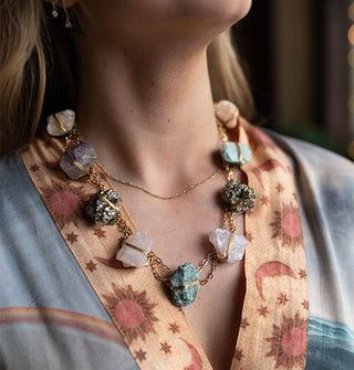 Model in sun, moon, and star print robe wears a wire-wrapped crystal necklace