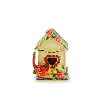 Decorative painted box designed to resemble a birdhouse with heart-shaped opening, red bird perched on one corner, rose accents, and a gold-edged opening is accented with clear and red crystals