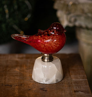 Small flecked red glass bird figurine affixed to a marble base with metal hardware