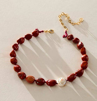 Necklace with gold clasp and extender chain is strung with polished red jasper stones and one accent seashell