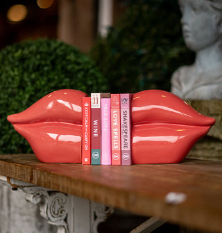 Pair of red ceramic bookends holding a small stack of books resemble a pair of lips