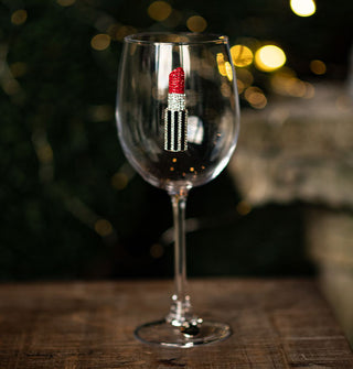Wine glass features a rhinestone-encrusted emblem of a striped tube of red lipstick