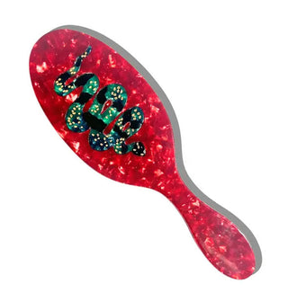 Hairbrush with red quartz effect features a central black and green snake design on its paddle