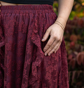Closeup of the elastic waistband on a plum-colored floral lace skirt with ruffled edges