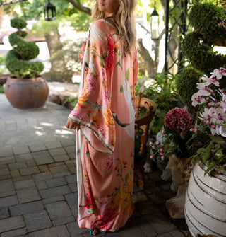 Model wears a maxi-length pink kimono-style robe with large floral and cranes print and contrast stripes along the hems