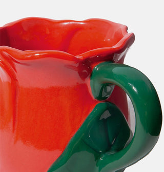 Closeup of the colors and details on a red and green ceramic rose mug