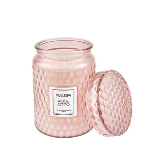 Pink geometrically embossed Voluspa Rose Otto jar candle with matching lid removed and propped alongside