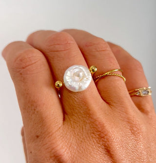 Model wears a gold and pearl ring with other thin gold ring bands
