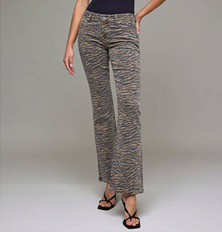 Model with one hand on hip wears a pair of flared tiger stripe jeans paired with strappy black heels