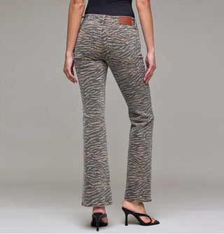 Model facing away from the camera wears a pair of flared tiger stripe jeans paired with strappy black heels