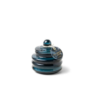 Small dark blue ribbed glass Saltwater + Suede scent candle jar with round tag hanging from its knobbed lid