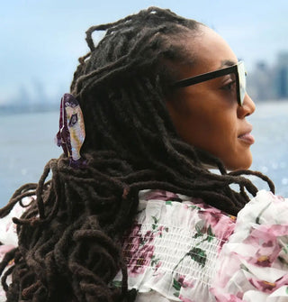Model wears a sardine claw clip in partially pulled-back dreadlocks 