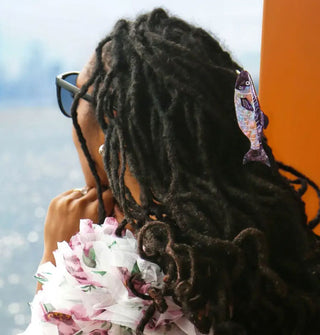 Model wears a sardine claw clip in partially pulled-back dreadlocks 